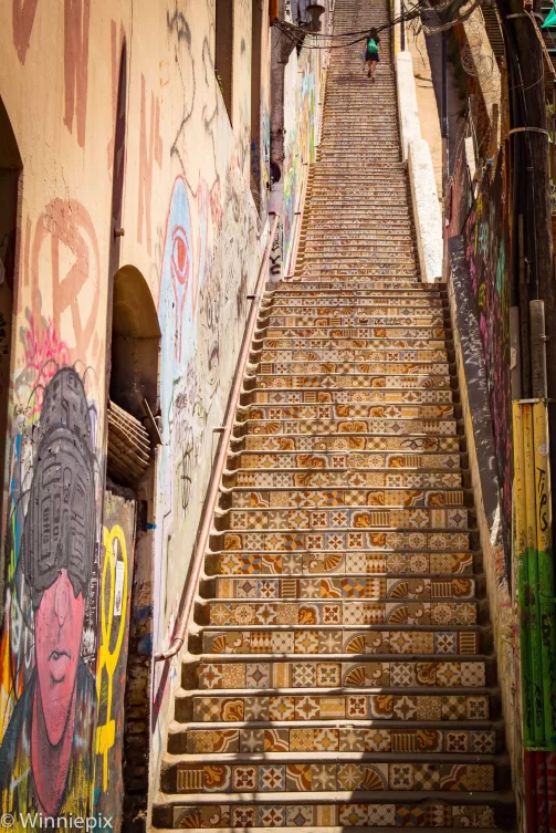 Tiled staircase in Valparaiso, Chile with street art on the walls either side