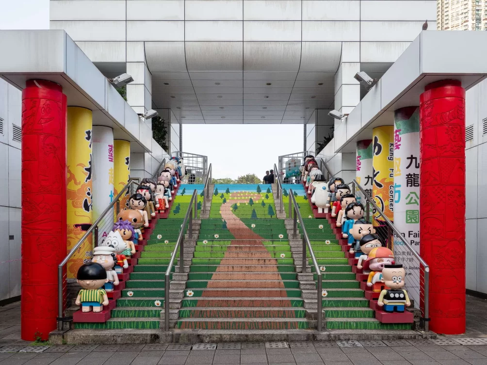 A staircase painted to look like a winding path through a field, with 3D cartoon style figures lining each side