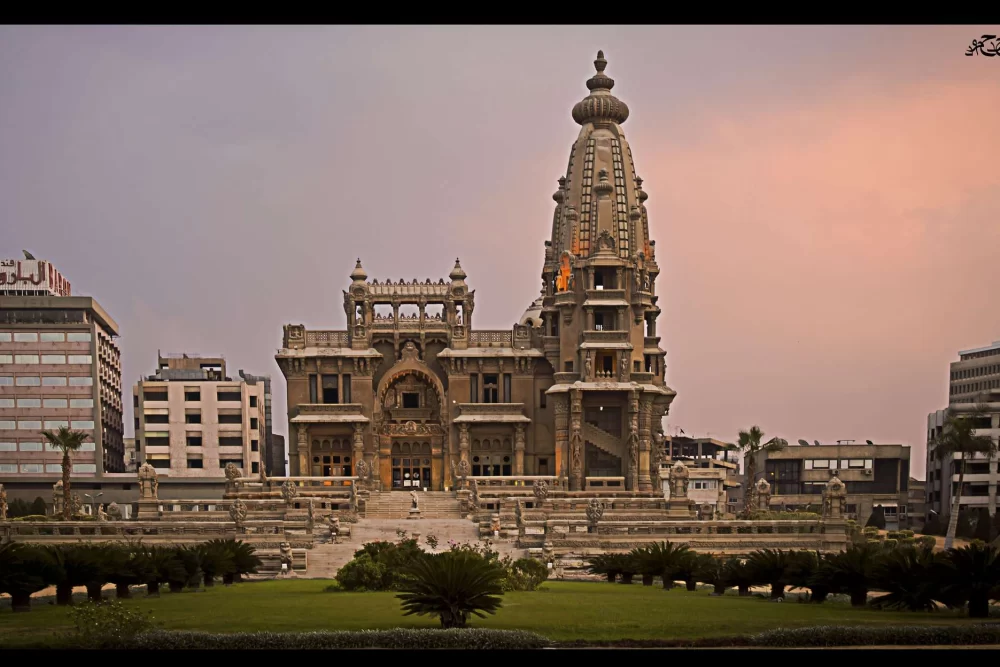 Baron Empain Palace at dusk with modern hotel buildings either side