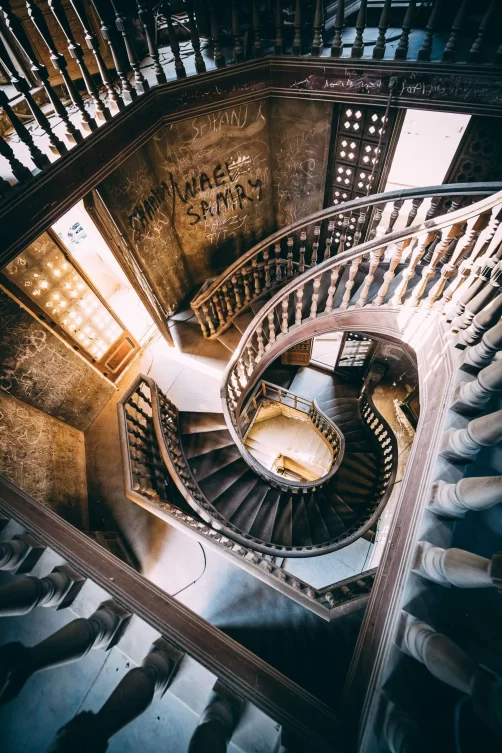 Looking down on the spiral staircase inside the derelict palace, with graffiti on the walls